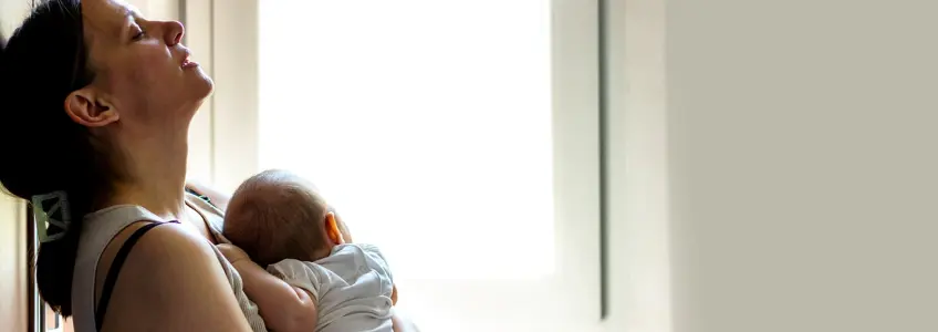 mãe com ar cansado segura bebé ao colo