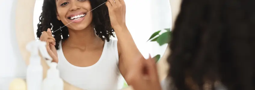 mulher a usar fio dentário