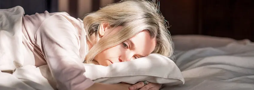 mulher deitada na cama com ar deprimido
