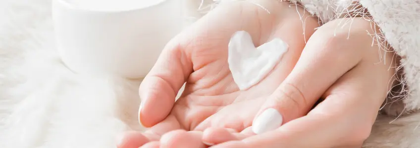 mulher com creme nas mãos em forma de coração