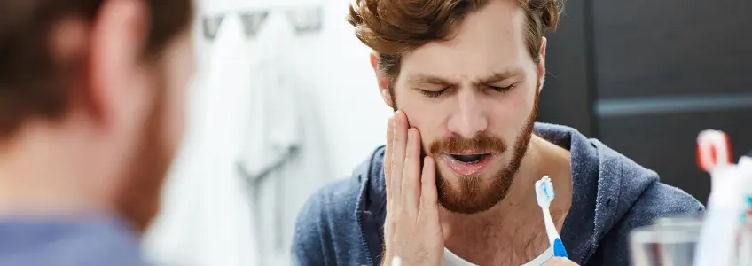 rapaz sente dor de dentes durante a escovagem