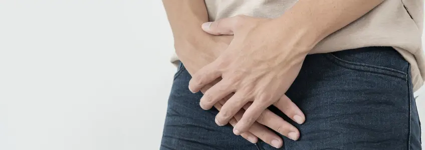 homem com as mãos em frente à braguilha