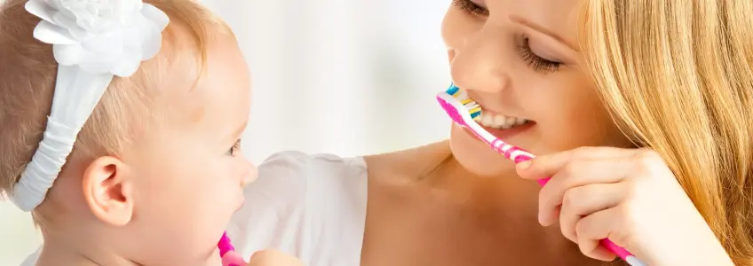 mãe ensina filha a lavar os dentes