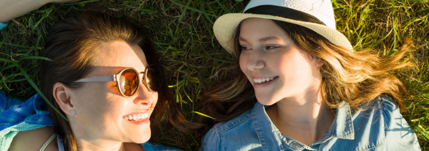 mãe e filha deitadas na relva felizes