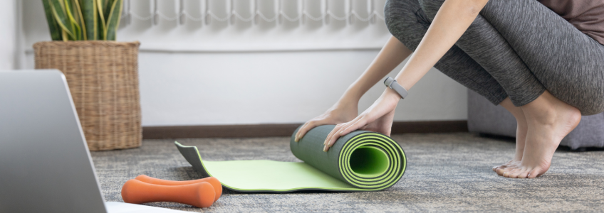 mulher a enrolar o tapete de yoga