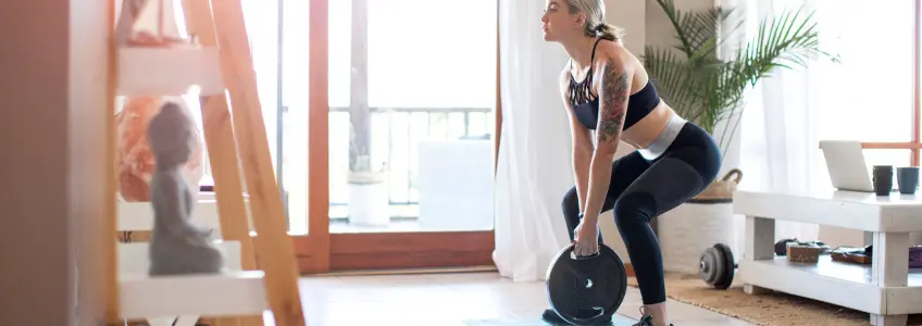 mulher em casa a fazer agachamento com disco