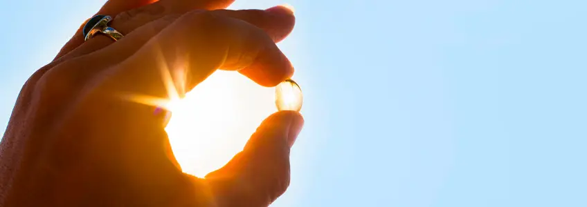 pessoa a segurar uma cápsula de vitamina D