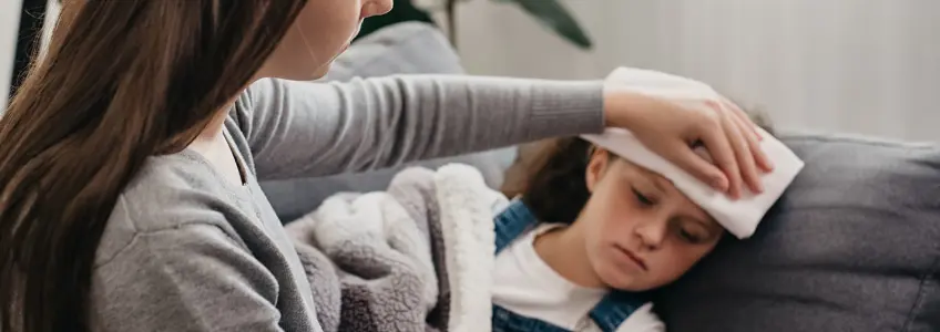 mãe aplica compressa na testa da filha