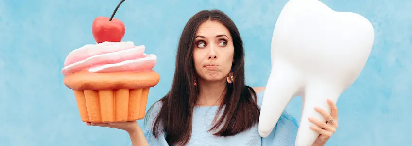 mulher a segurar em molde de dente numa mão e bolo no outro