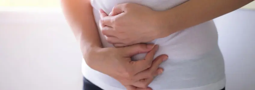 mulher com as mãos a pressionar a zona abdominal