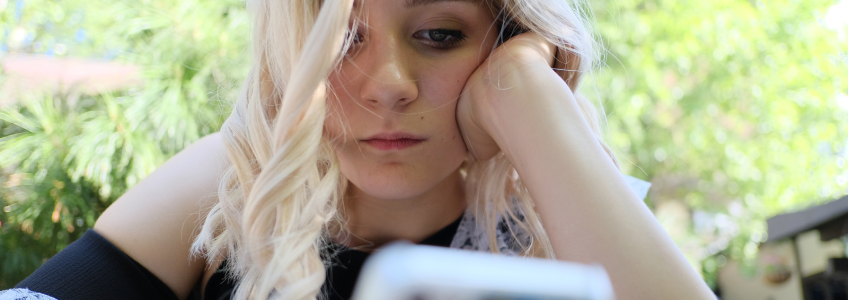 adolescente triste a olhar para o telemóvel