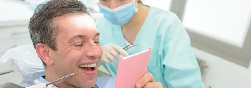 paciente vê-se ao espelho após colocação de implante dentário