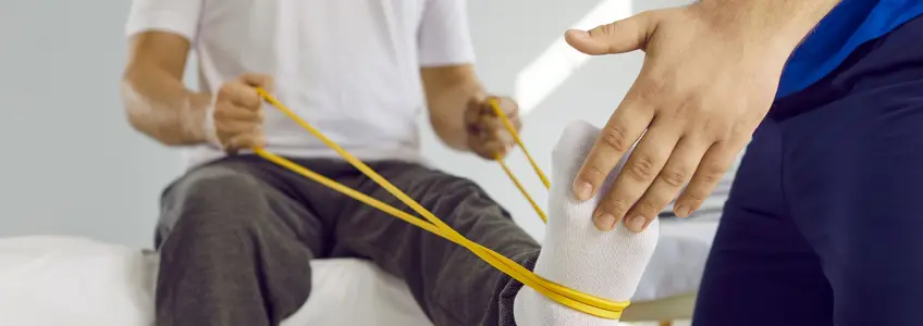 homem com elástico e acompanhado por fisioterapeuta