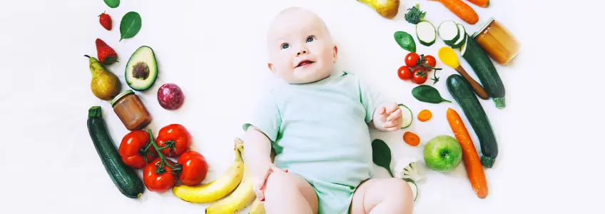 bebé rodeado de alimentos sólidos