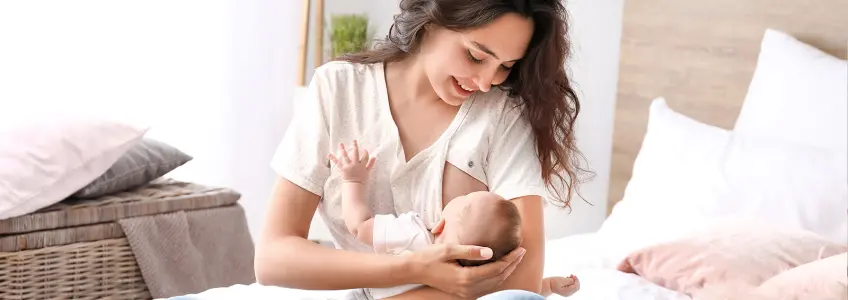 mãe a amamentar bebé em cima da cama
