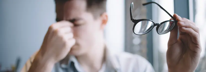 homem com óculos na mão e olhos fechados