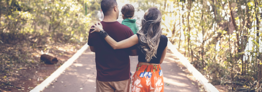 Família com uma criança a caminhar num bosque