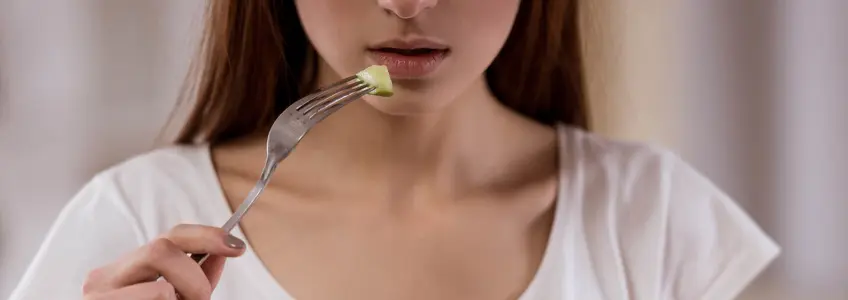 rapariga a ingerir um pequeno pedaço de pepino