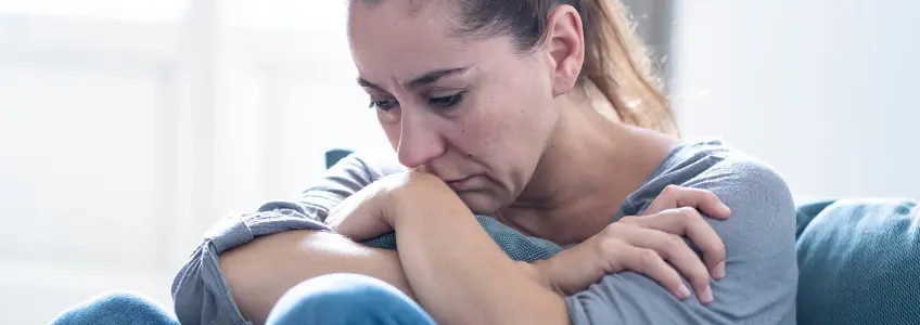 mulher sentada no sofá com um ar triste