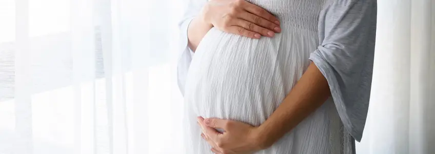 mulher a acariciar a barriga em casa