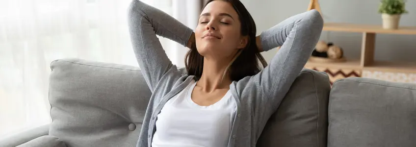 rapariga sentada no sofá a sorrir de olhos fechados