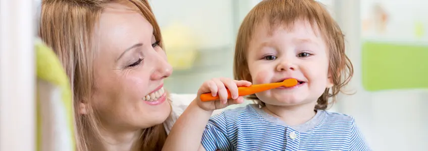 mãe ajuda filha a lavar os dentes