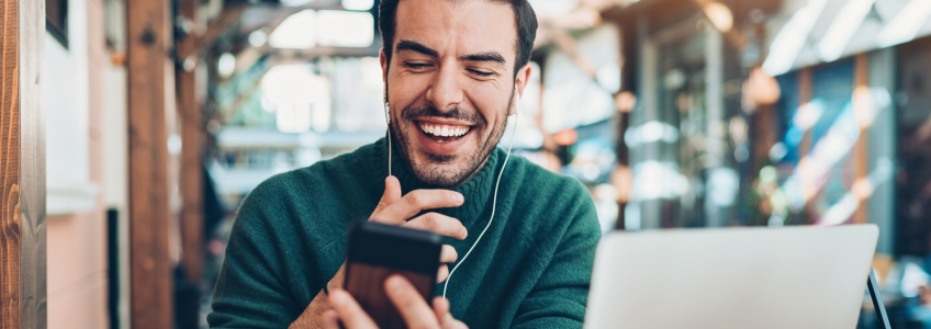 Homem a sorrir para o telefone em teletrabalho