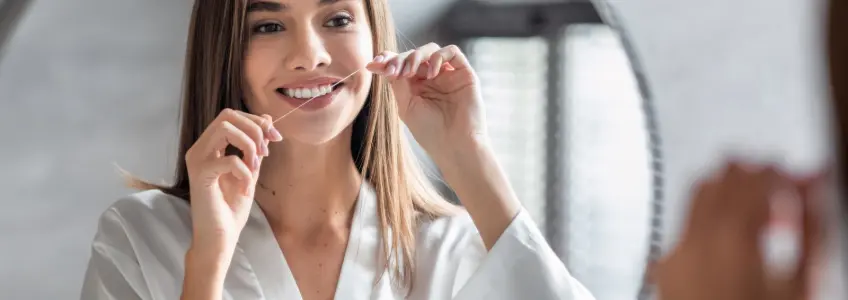 rapariga a usar fio dentário