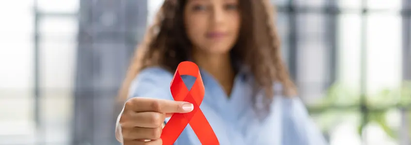 mulher a segurar laço vermelho símbolo da luta contra a Sida