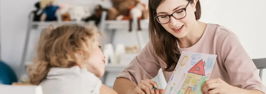 terapeuta e menina observam desenho