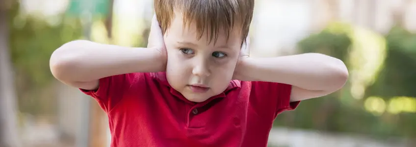 menino com síndrome de asperger a tapar os ouvidos