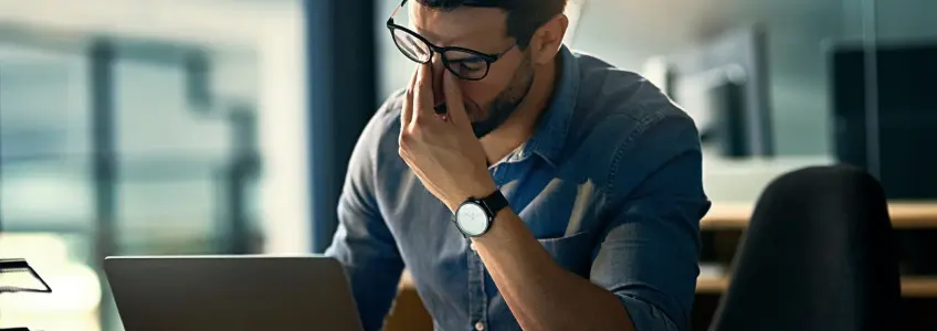 homem com ar preocupado e cansado em frente ao computador 