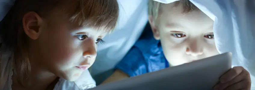 duas crianças na cama com o tablet na mão