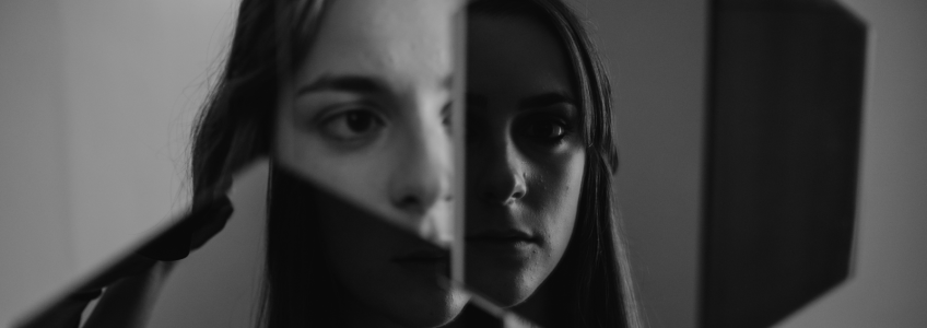 mulher com a imagem fragmentada ao espelho