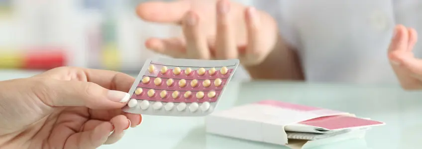 mulher com a embalagem da pílula na mão