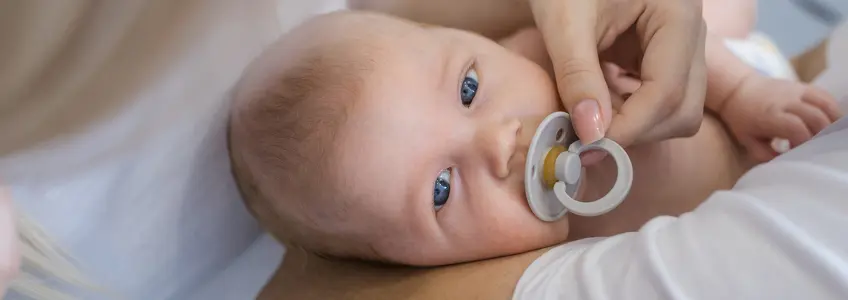 bebé com chupeta deitado no colo da mãe