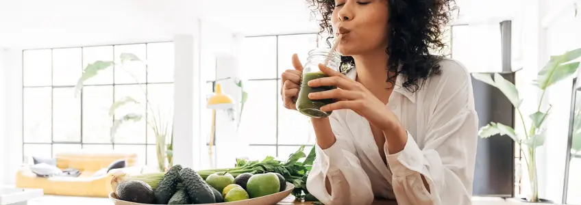 mulher a beber um sumo de fruta e legumes