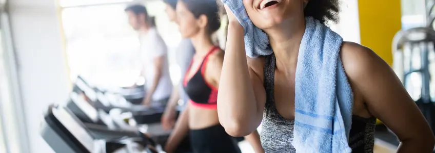mulher pós-treino a limpar o suor na passadeira