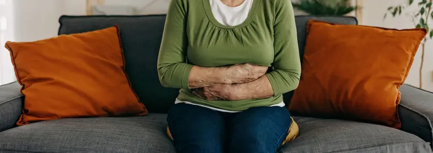 mulher sentada no sofá com braços cruzados na barriga