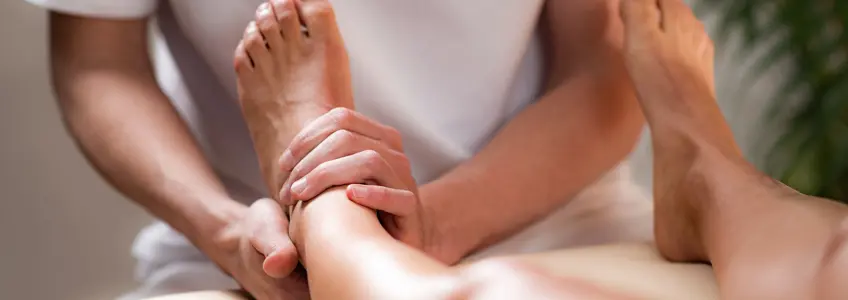 homem sentado na cama a massagear o pé