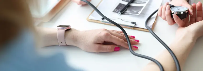 médico a avaliar tensão arterial com ecografia e relatório médico na secretári